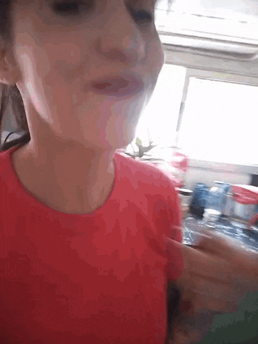 a girl in a red shirt is holding a bottle of water