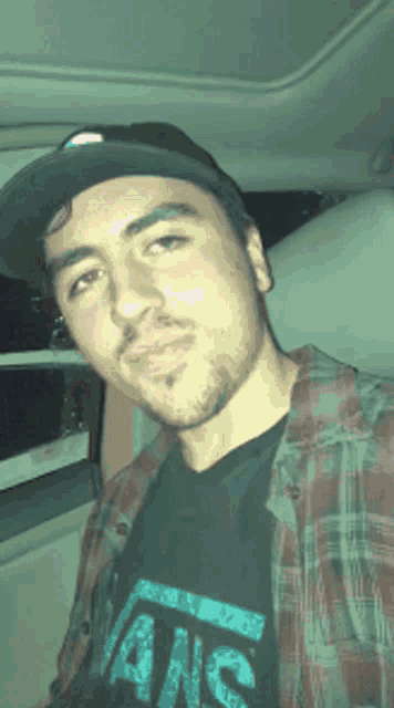 a man wearing a plaid shirt and a black vans shirt