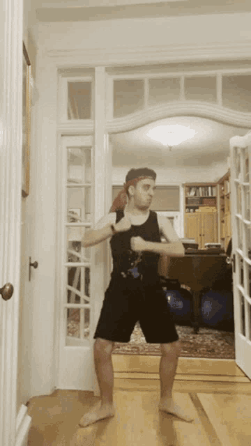 a man in black shorts and a red headband is dancing in a room