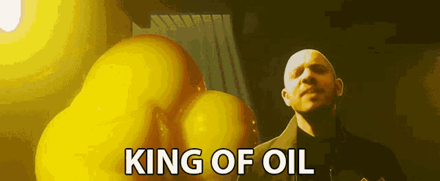 a bald man is standing in front of a bunch of yellow balloons with the words king of oil above him