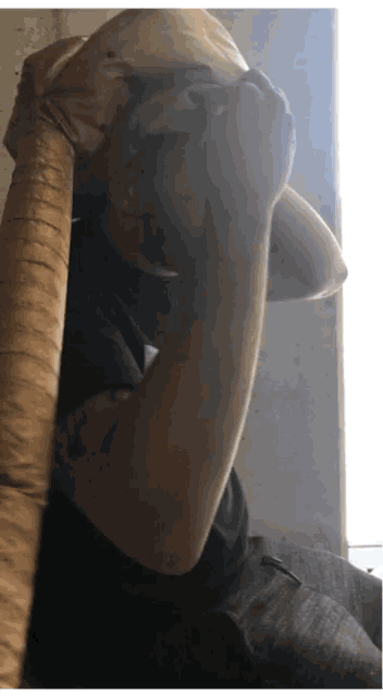 a man in a black shirt is covering his face with his arm