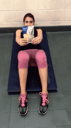a woman is sitting on a mat holding a bag of chips in front of her face .