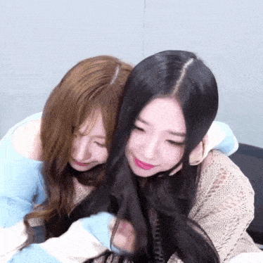 two girls hugging each other with one wearing a blue and white sweater