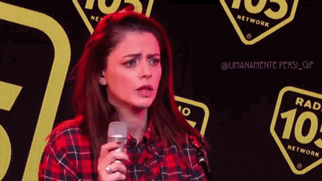 a woman is singing into a microphone in front of a radio network logo