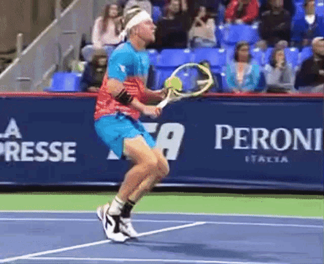 a tennis player is swinging a tennis racquet on a tennis court with a peroni banner behind him