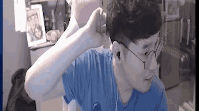 a man wearing a blue shirt and glasses is adjusting his ear buds