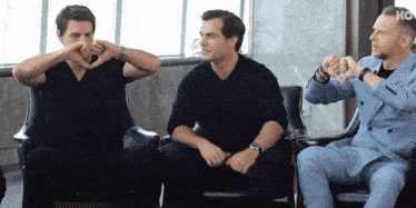 three men are sitting in chairs and one of them is wearing a watch that says ko