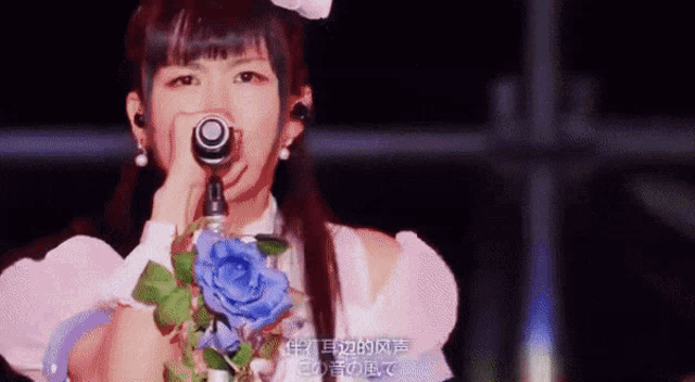 a girl singing into a microphone with chinese writing on the bottom