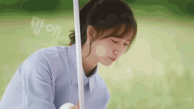 a woman in a blue shirt is sitting in the grass holding a white pole .