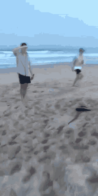 a man in a white shirt and shorts is running on the beach
