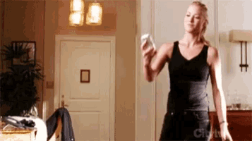 a woman in a black tank top is looking at her cell phone