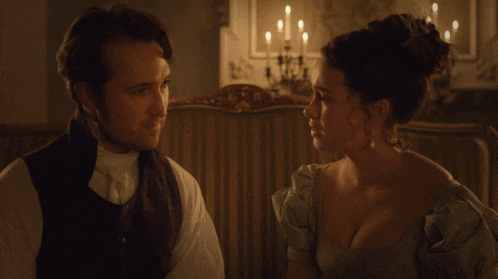 a man and woman looking at each other in a dark room