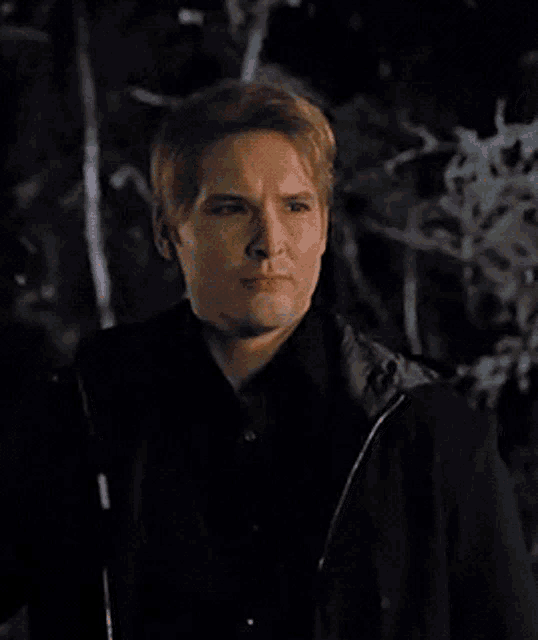 a man in a black shirt and jacket is looking down at something