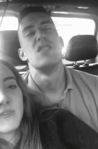 a man and a woman are sitting in a car and the man is making a funny face