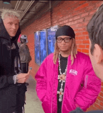a man wearing a pink jacket that says miami is talking to another man