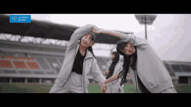 a group of girls are stretching in front of a sign that says upfront world