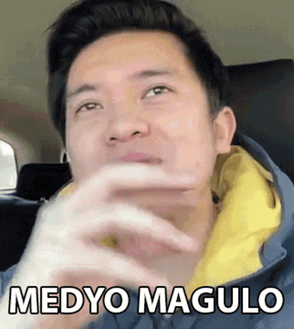 a man is sitting in the back seat of a car and making a funny face with the words medyo magulo written on his face