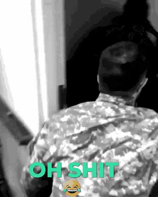 a man in a camo shirt is standing in front of a door that says oh shit