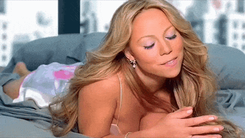 a woman with long blonde hair is laying on a bed with her eyes closed