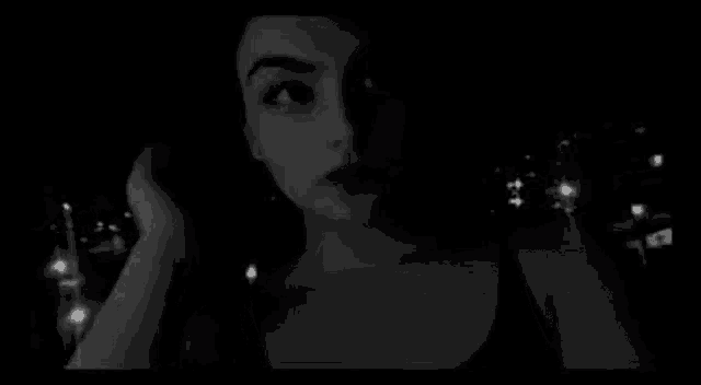 a black and white photo of a woman in a black tank top .