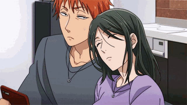a man and a woman are sitting next to each other and the man is looking at a cell phone