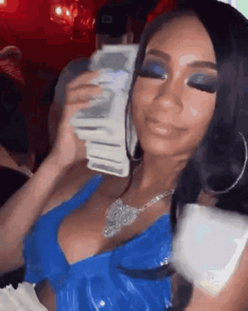 a woman in a blue dress is holding a stack of money in her hands .