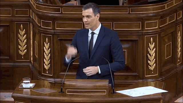 a man in a suit stands at a podium with a long nose