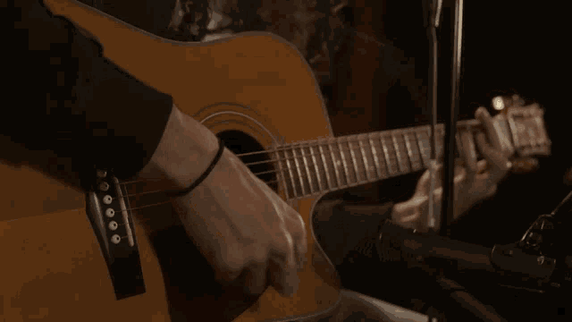 a person playing an acoustic guitar with a black wristband