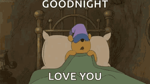winnie the pooh is sleeping in a bed with a blanket and a sleep mask on .