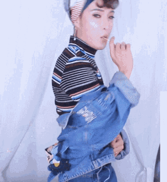 a woman wearing a denim jacket and a striped shirt