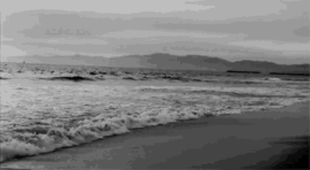 a black and white photo of waves on a beach
