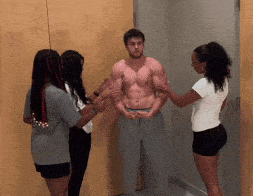 a shirtless man is surrounded by two women