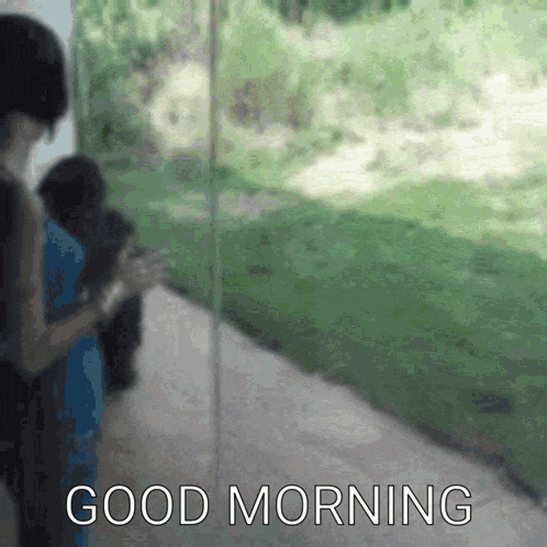 a blurred image of a person standing next to a sign that says " good morning "