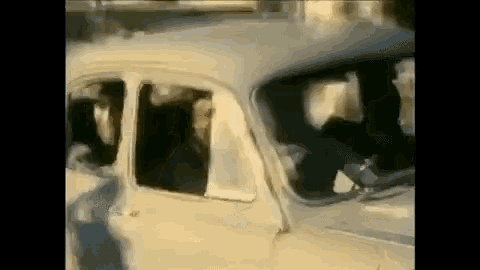 a white car with a broken windshield is driving down a street .
