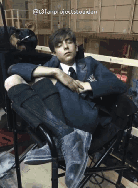 a young man in a suit and tie is laying on a chair with the hashtag @t3fanprojectstoaidan