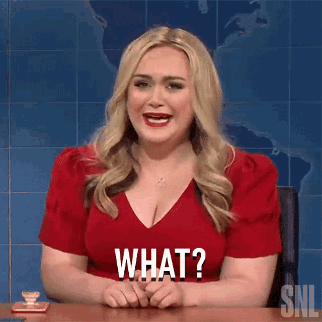 a woman in a red dress is sitting at a desk and says what .