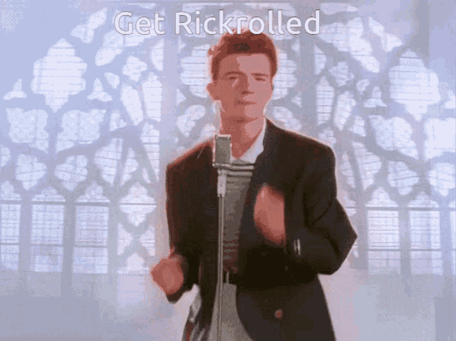 a man singing into a microphone with the words get rickrolled written below him