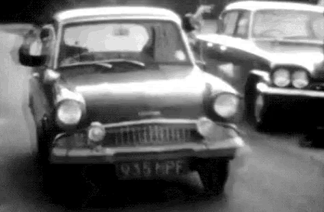 a black and white photo of a small car driving down a street .