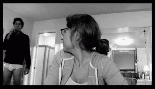 a black and white photo of a woman wearing glasses and a man in underwear