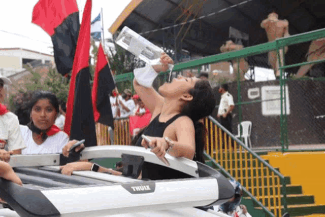 a woman is drinking water from a thule rack