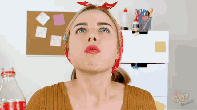 a woman wearing a bandana and a bottle of coke looks up