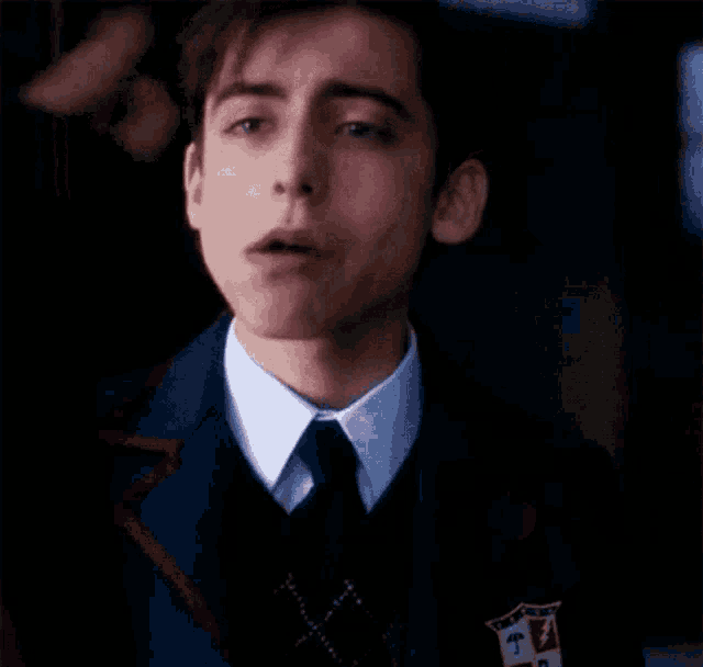 a close up of a young man in a suit and tie looking at the camera .