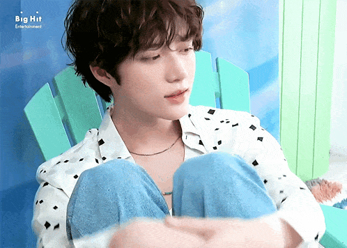 a young man sits in a green chair with big hit entertainment written on the bottom right