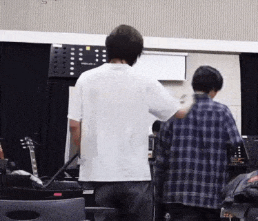 a man in a plaid shirt is standing next to another man in a white shirt in a room .