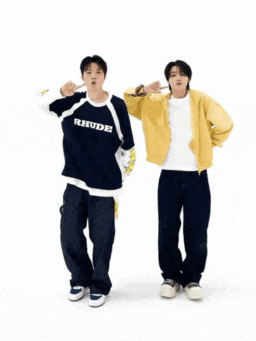 a man in a blue shirt with the word rbu on it is standing next to another man in a yellow jacket