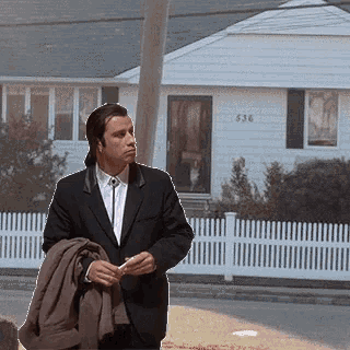 a man in a suit is standing in front of a house with 536 on the front