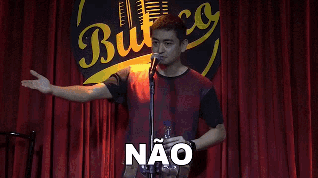 a man stands in front of a microphone with the word não written on the bottom