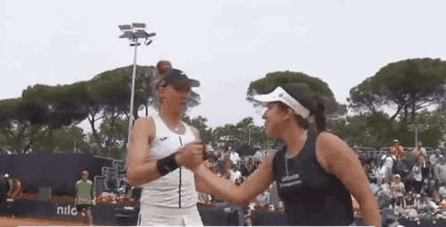 two women shaking hands on a tennis court with a banner that says nile