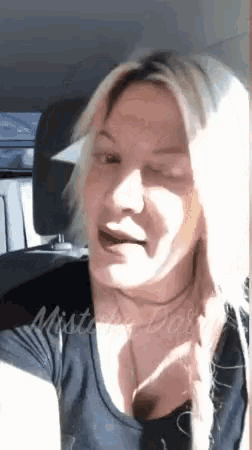 a woman with blonde hair is sitting in the back seat of a car