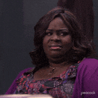 a woman wearing a purple sweater and a floral dress is making a face .